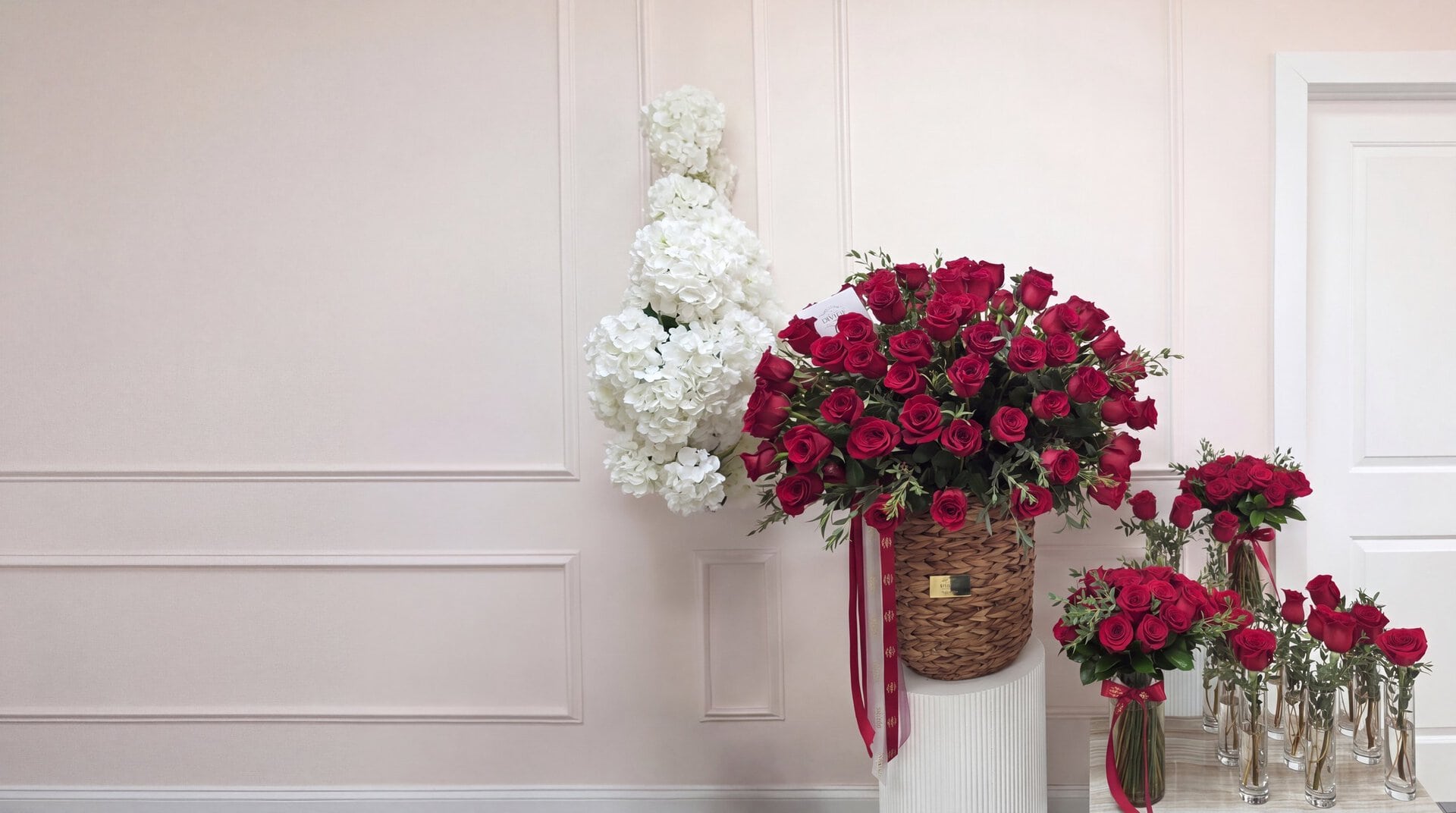 El juego completo para un jet privado en el taller de My Divine Decors en Doral: canasta tejida de rosas rojas sobre un pedestal, un florero de rosas rojas con lazo y rosas sueltas en floreros altos