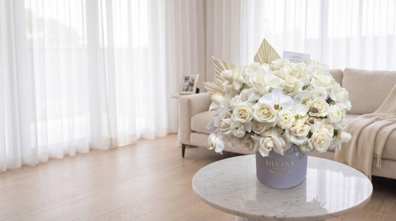 Celine hat box by My Divine Decors with white roses, ranunculus and orchids on a marble table in the quiet living room of a Miami family home