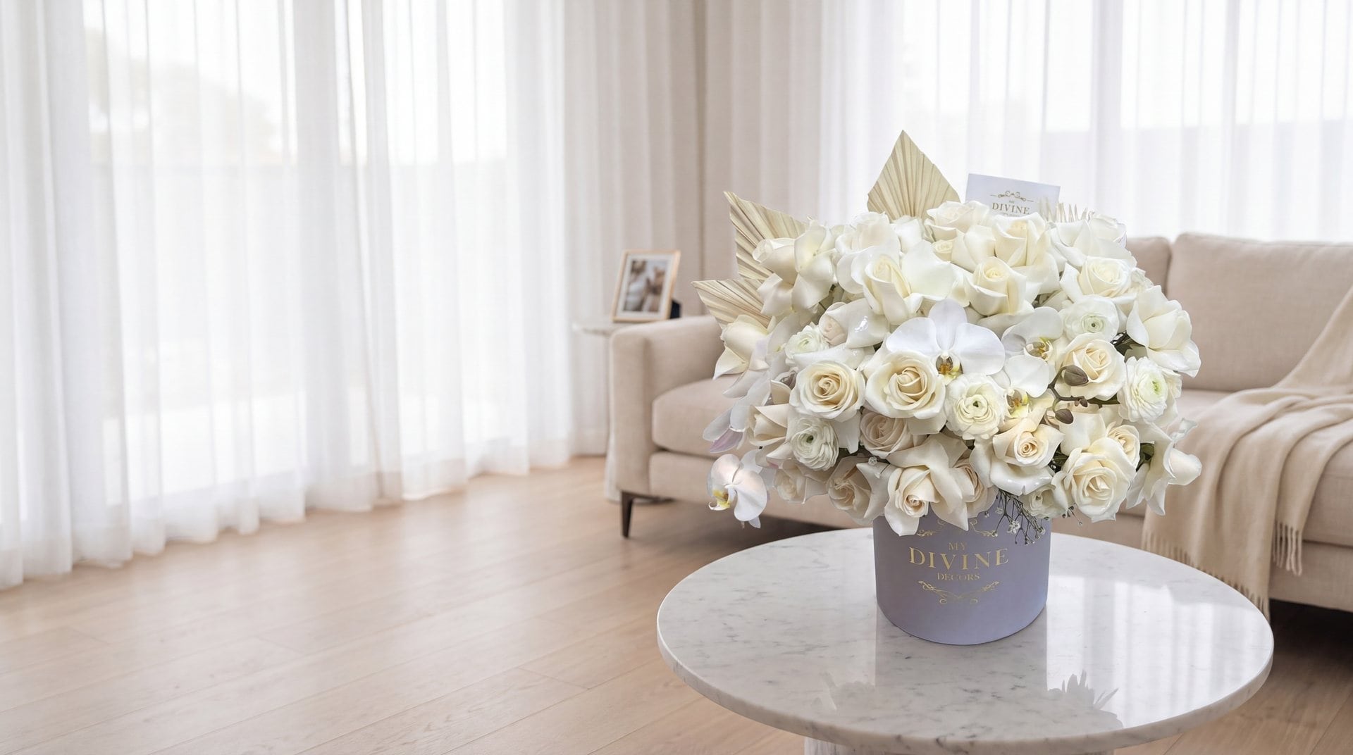 Celine hat box by My Divine Decors with white roses, ranunculus and orchids on a marble table in the quiet living room of a Miami family home